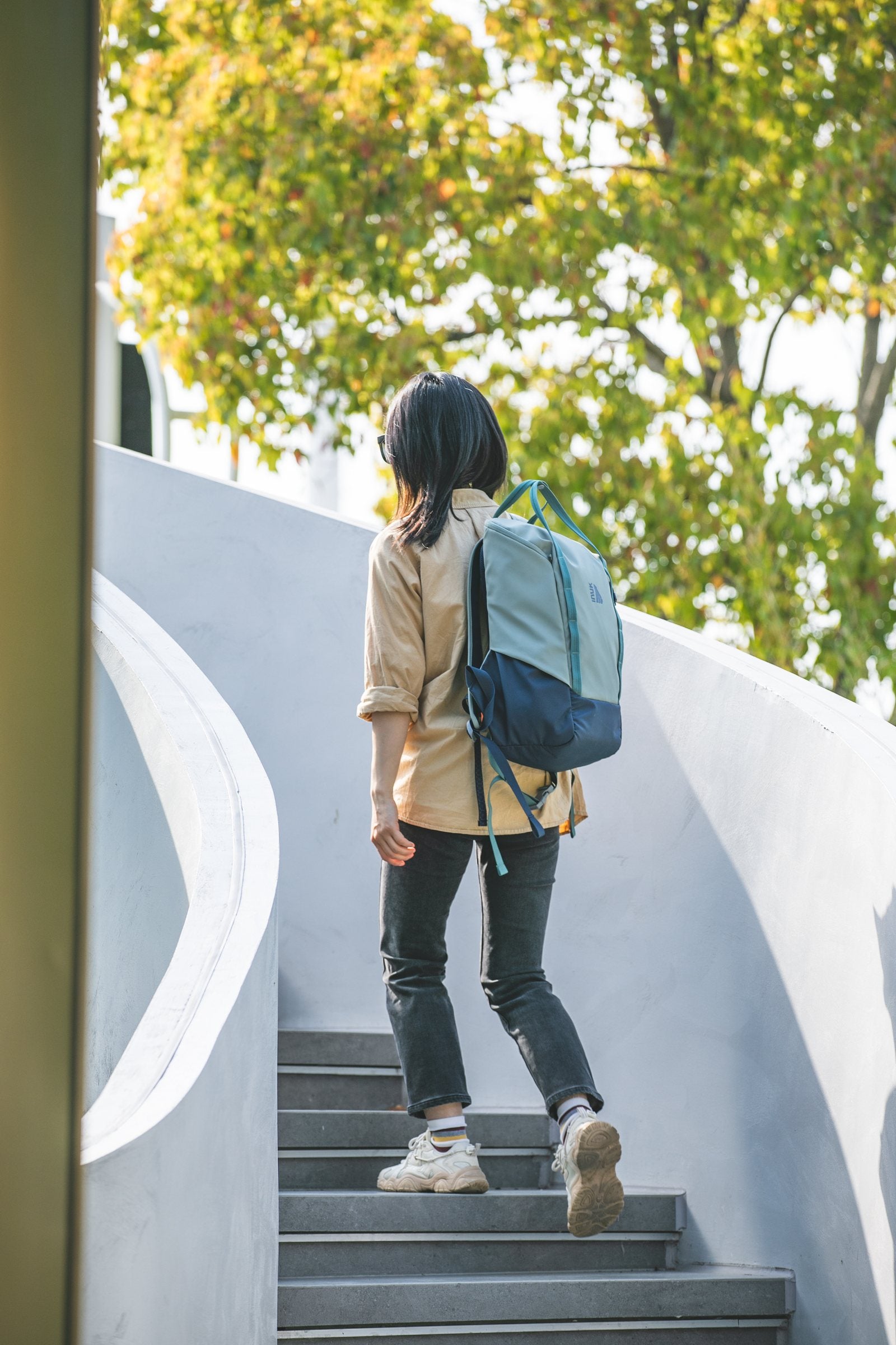 Person climbing outdoor stairs while wearing the Sage Leaf CRUISER backpack